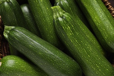 Raw ripe zucchinis in wicker bowl, closeup