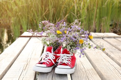 Shoes with beautiful flowers on deck outdoors