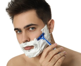 Handsome young man shaving with razor on white background