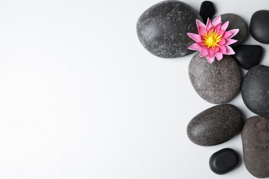 Stones with lotus flower and space for text on white background, flat lay. Zen lifestyle