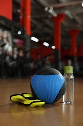 Medicine ball, bottle and weighting agents on floor in gym