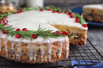 Traditional Christmas cake decorated with rosemary and pomegranate seeds on grey table, closeup