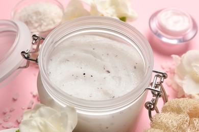Body scrub in glass jar on pink background, closeup