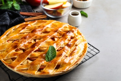 Fresh traditional apple pie with mint on light grey table