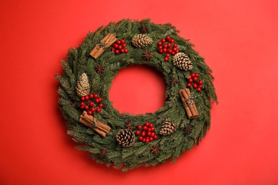 Beautiful Christmas wreath on red background, top view