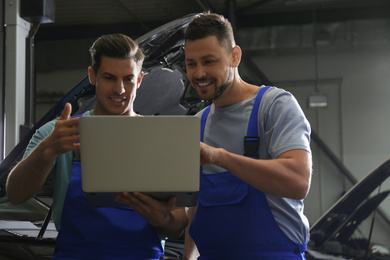 Photo of Mechanics with laptop doing car diagnostic at automobile repair shop