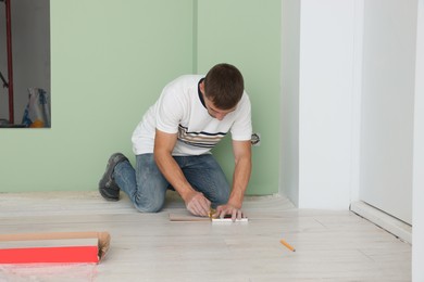 Man using pencil during installation of new laminate flooring in room