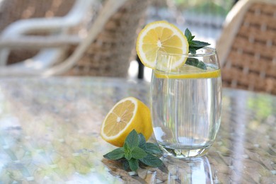 Photo of Refreshing water with lemon and mint on glass table in cafe, space for text