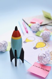 Composition with toy rocket and stationery on light blue background. Startup concept