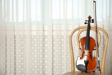 Classic violin and bow on chair indoors. Space for text