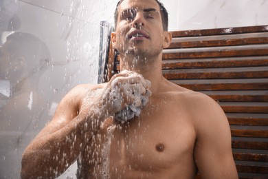 Man with mesh pouf taking shower at home