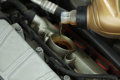Pouring motor oil into car engine at automobile repair shop, closeup