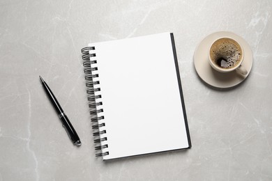 Open blank notebook, pen and coffee on light grey marble table, flat lay