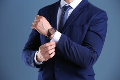 Businessman with wristwatch on color background. Time concept