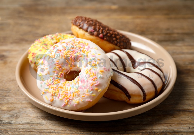 Photo of Sweet delicious glazed donuts on wooden table