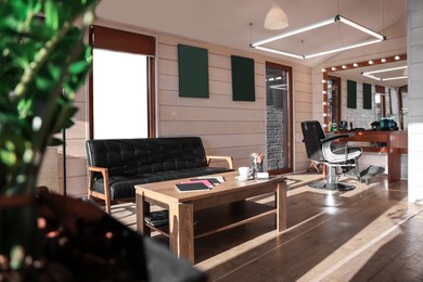 Photo of Stylish barbershop interior with hairdresser workplace, leather sofa and coffee table