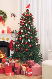 Beautiful Christmas tree and gift boxes near decorated fireplace in room