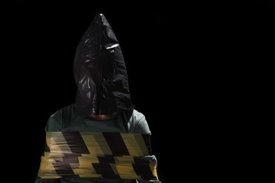 Photo of Little boy in plastic bag tied up and taken hostage on dark background. Space for text