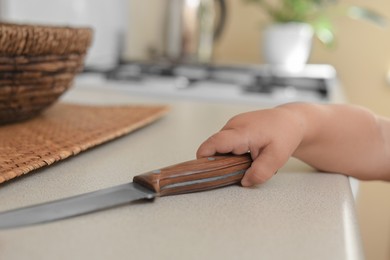 Photo of Child holding sharp knife, closeup. Dangers in kitchen