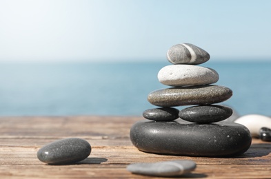 Stack of stones on wooden pier near sea seascape, space for text. Zen concept