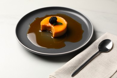 Photo of Delicious pudding with caramel and blackberry on white marble table
