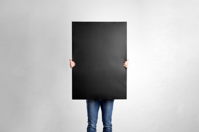 Man holding blank poster on light grey background
