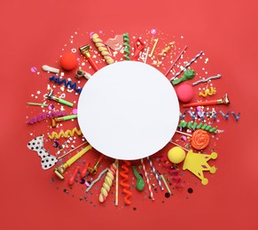 Photo of Frame of festive items on red background, flat lay with space for text. Surprise party concept