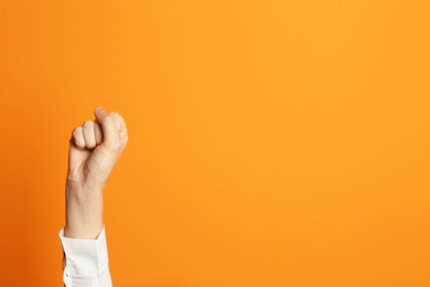 Young woman showing clenched fist on color background. Space for text