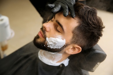 Young man visiting barbershop. Professional shaving service