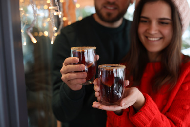 Lovely couple with tasty mulled wine outdoors, focus on hands