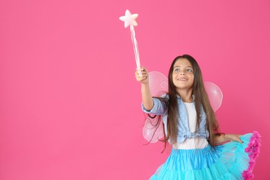 Cute little girl in fairy costume with wings and magic wand on pink background. Space for text