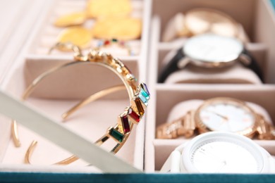 Photo of Beautiful bracelets and wristwatches in jewelry box, closeup