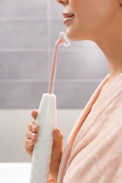 Woman using high frequency darsonval device in bathroom, closeup