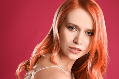 Beautiful woman with long orange hair on pink background