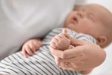 Mother holding her cute sleeping baby, focus on hands