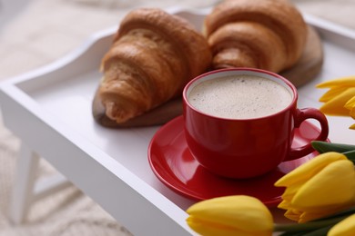 Morning coffee, flowers and croissants on white wooden tray, closeup. Space for text