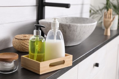 Dispensers with liquid soap on countertop in bathroom
