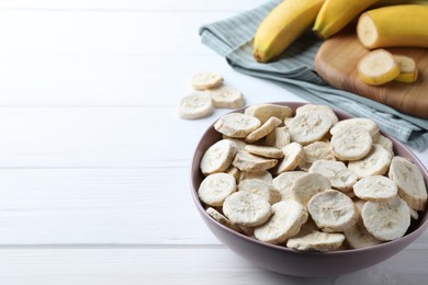 Freeze dried and fresh bananas on white wooden table. Space for text
