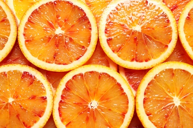Juicy blood orange slices as background, top view. Citrus fruit