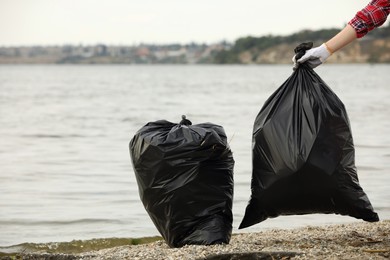 Woman with trash bags full of garbage on beach, closeup