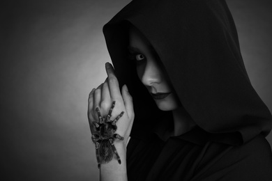 Mysterious witch with spooky spider on dark background, space for text. Black and white effect