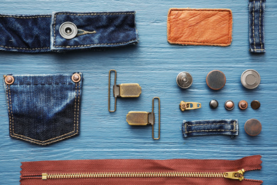 Photo of Flat lay composition with garment accessories and cutting details for jeans on light blue wooden background