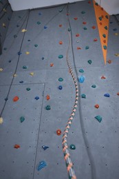 Climbing wall with holds and ropes in gym. Extreme sport