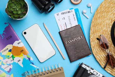 Flat lay composition with passport, tickets and travel items on light blue background