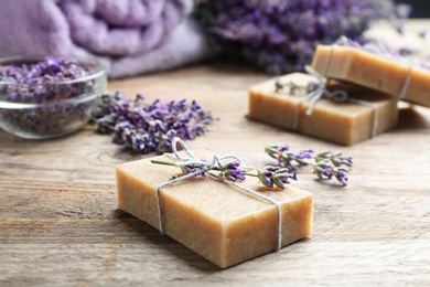 Handmade soap bars with lavender flowers on brown wooden table, closeup. Space for text