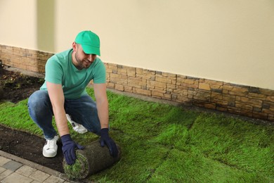 Photo of Worker laying grass sod on ground at backyard, space for text