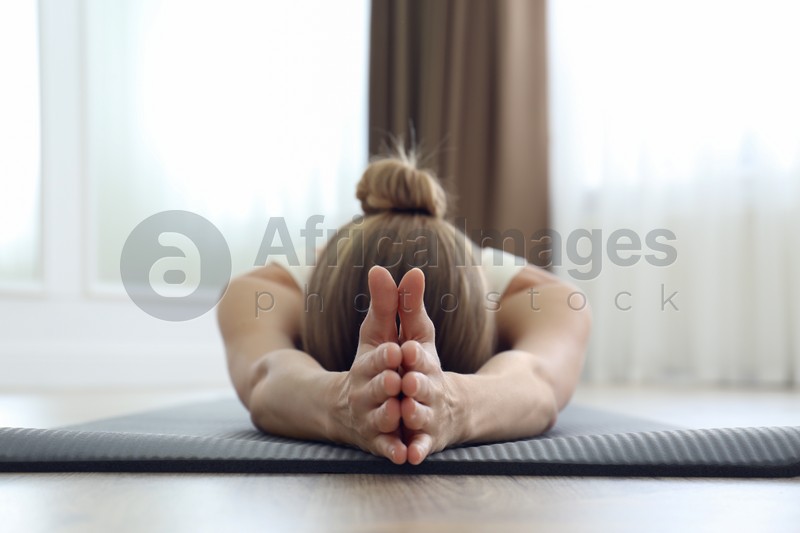 Young woman practicing restorative asana pose in yoga studio, focus on hands