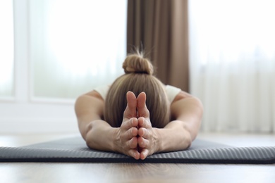 Young woman practicing restorative asana pose in yoga studio, focus on hands