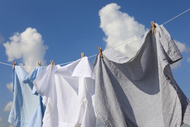 Photo of Clean clothes hanging on washing line against sky. Drying laundry