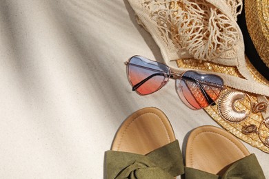 Flat lay composition with stylish sunglasses and other fashionable accessories on sand. Space for text